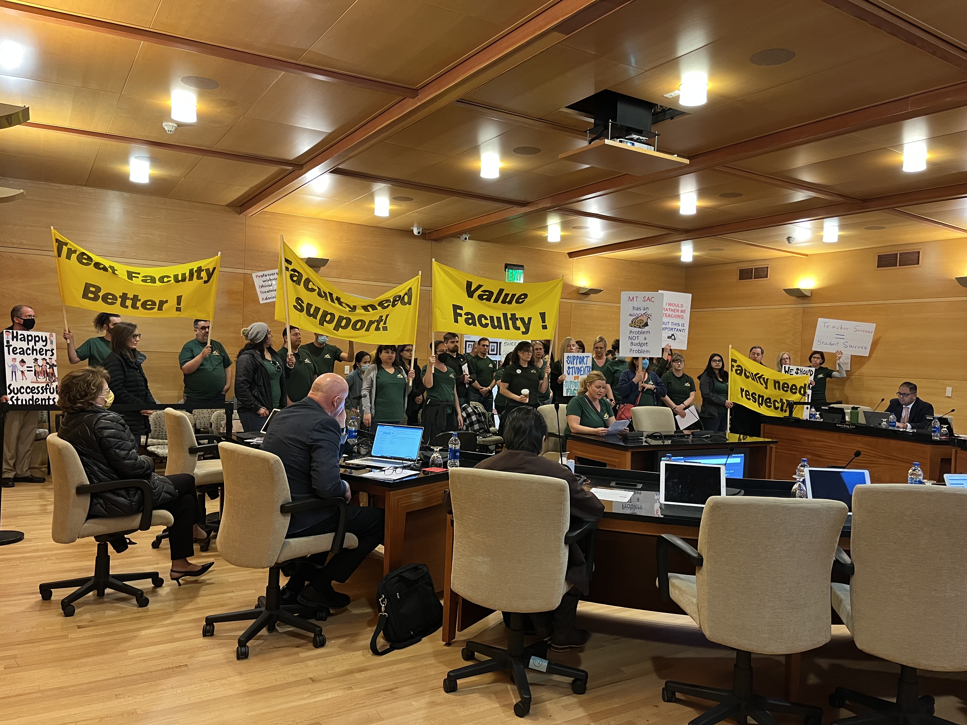 Faculty Association Members holding signs that express need for the District to value, respect, and support faculty at the Board of Trustees Meeting