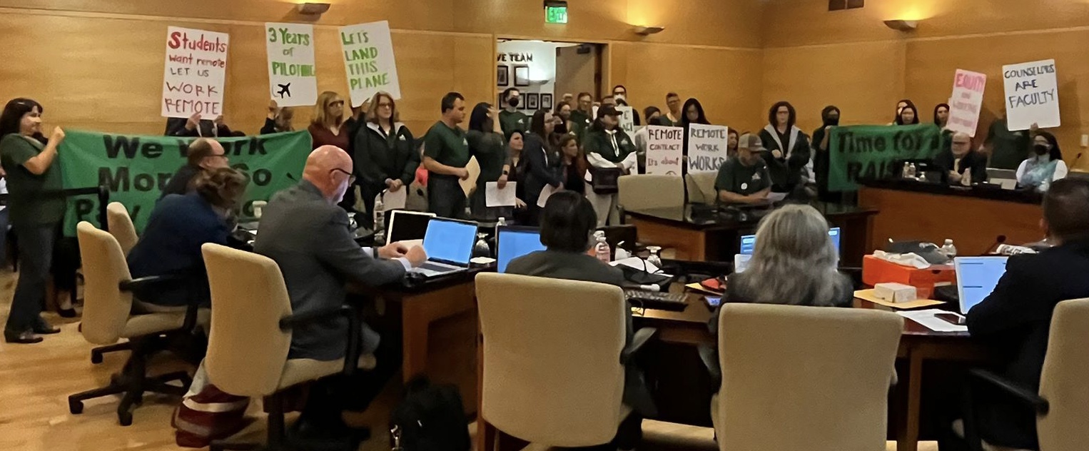 Faculty Association Members holding signs that express need for the District to value and support remote working conditions for all faculty at the Board of Trustees Meeting